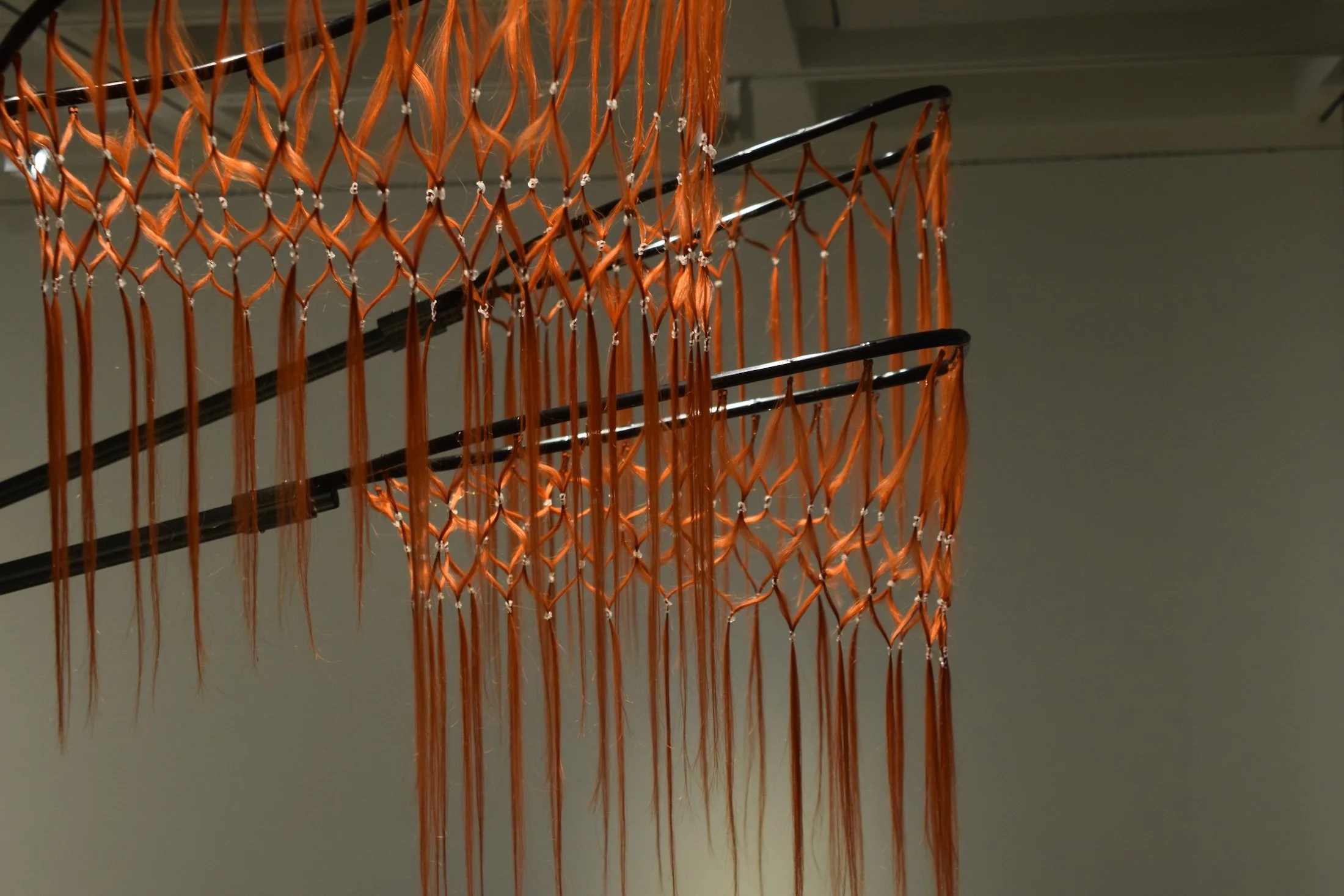 Jule Tabea Martin, sculpture with human hair extensions hanging from metal rods, installation view