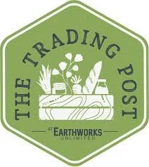 Logo for The Trading Post Earthworks Unlimited featuring a green hexagon shape with plants, a watering can, and gardening tools