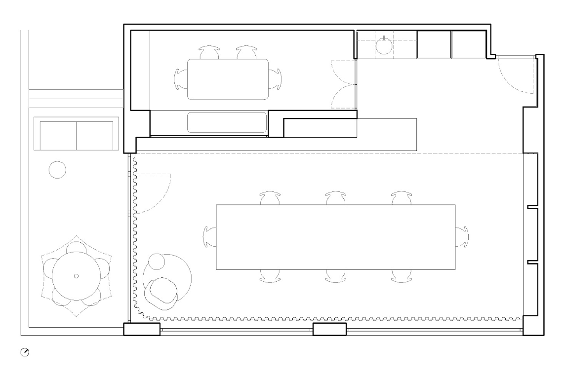 Floor plan of an open-concept office or conference room with a large table, chairs, a small meeting area with a round table and chairs, a lounge with seating, and a smaller enclosed room in the top corner.