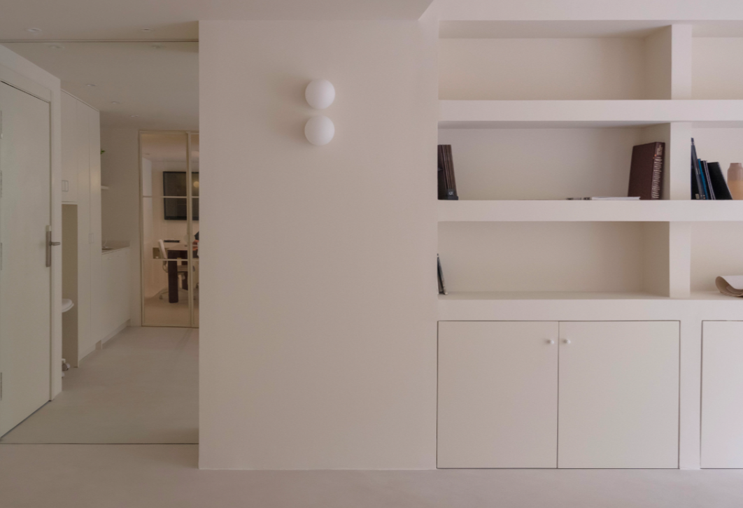White built-in shelves with books and closed cabinets in a minimalist room.