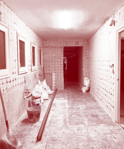 Construction site of an unfinished hallway with brick walls, construction materials, and tools.
