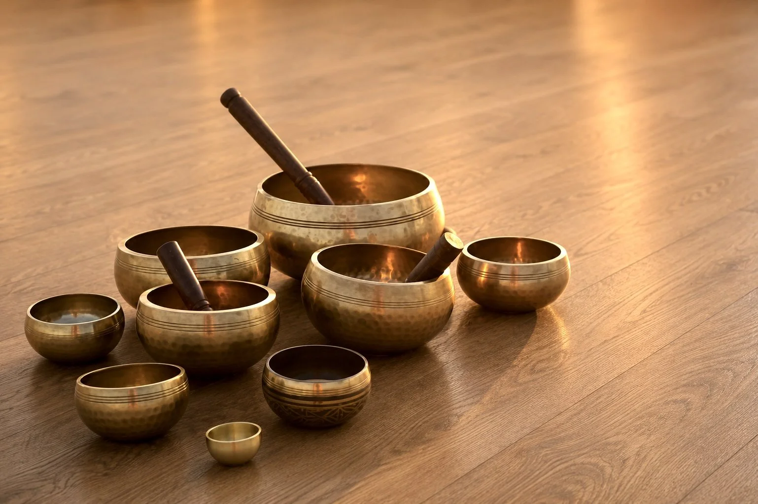 Set di campane tibetane di diversi diametri posizionate su un pavimento di legno.