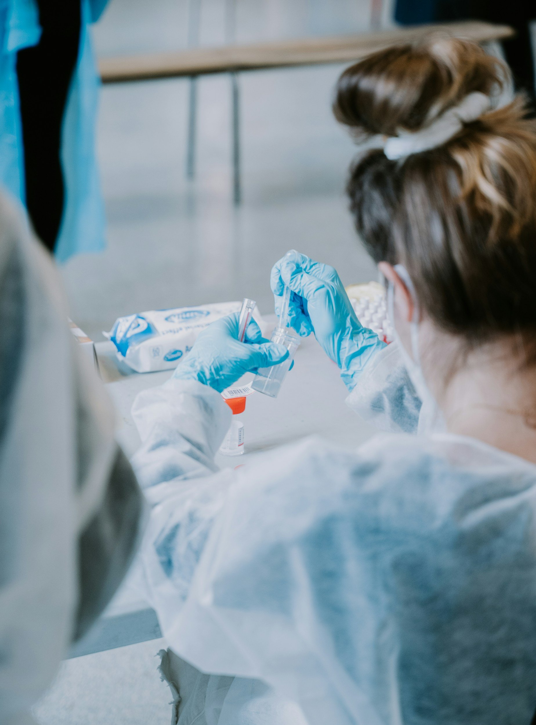 Researchers working with laboratory equipment, including a pipette and test tubes, in a scientific laboratory setting.