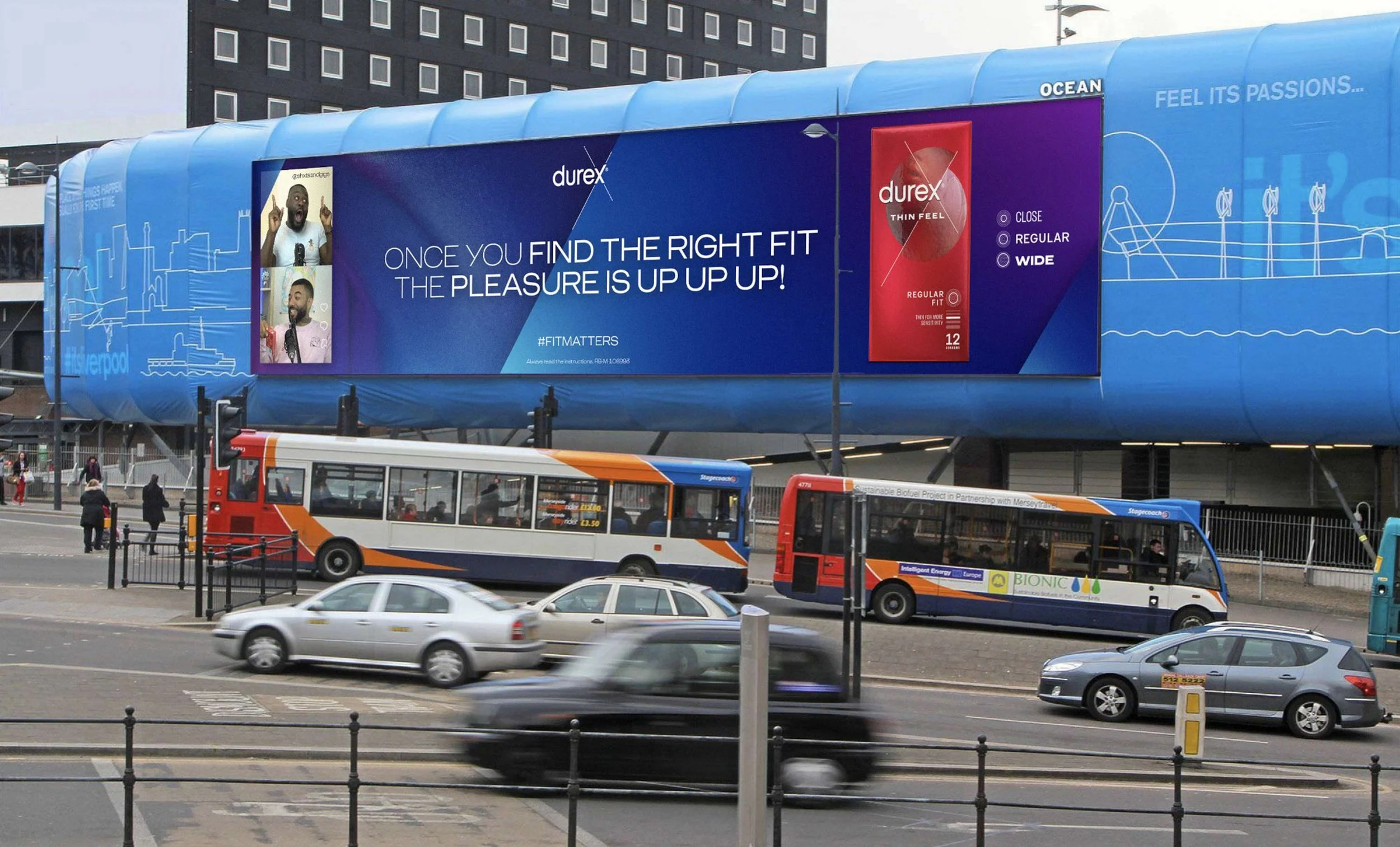 A city street scene with buses, cars, and pedestrians, featuring a large blue billboard advertising Durex condoms, with the slogan 'Once you find the right fit the pleasure is up up up!'