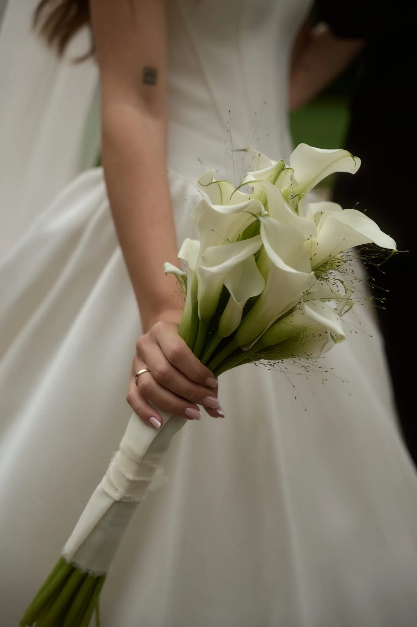 A bride holding a bouquet of white calla lilies at her wedding.