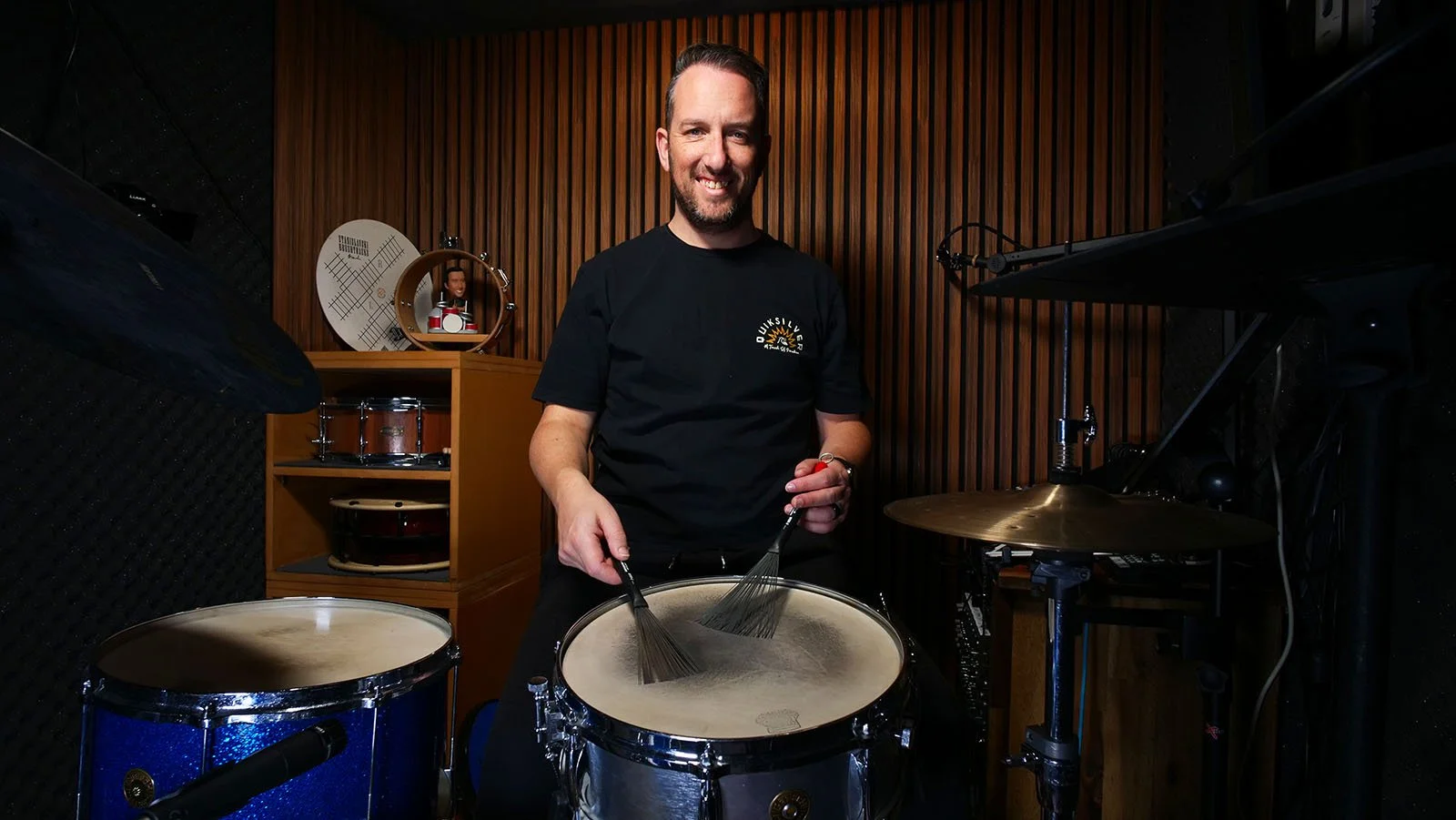 Brush expert Anthony Stanislavski, sitting down at his drum set in his studio, smiling, ready to teach