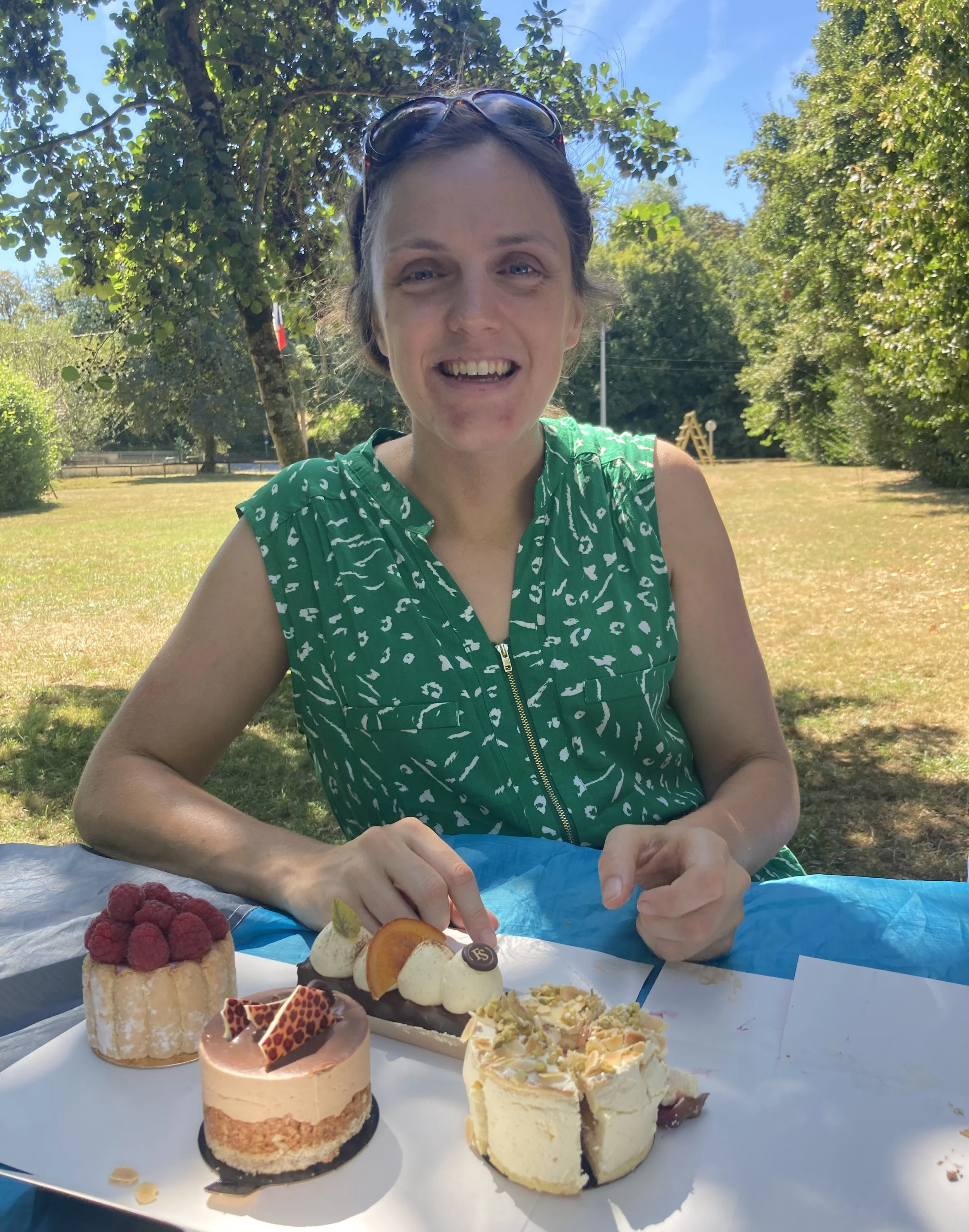 Jenny sitting outdoors at a table with assorted cakes and desserts on a white plate.
