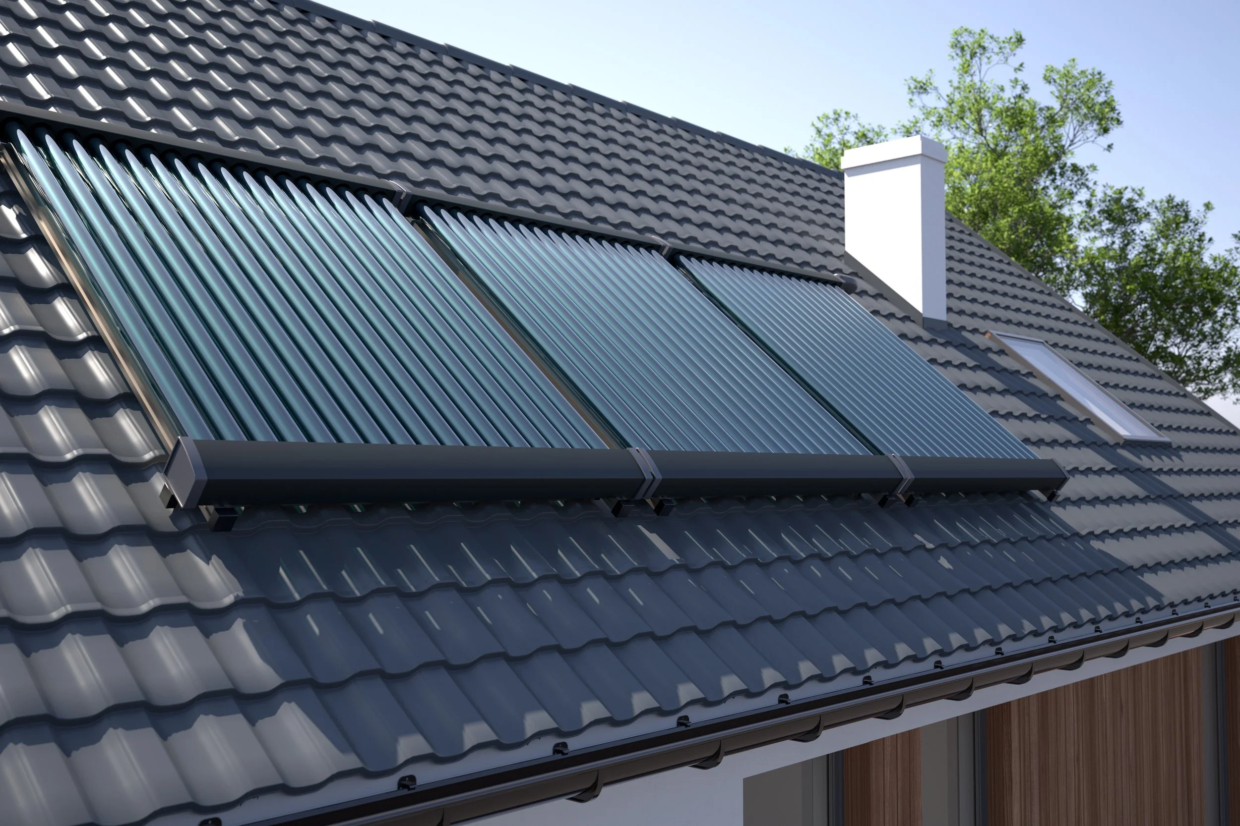 Solar thermal panels installed on a residential roof with dark gray tile roofing, a white chimney, a skylight, and green trees in the background.