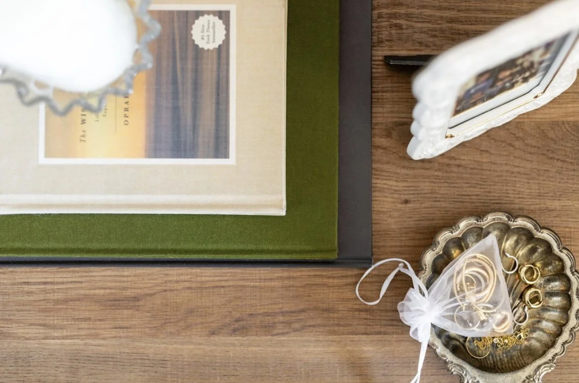 Decorative jewelry, a picture frame, a book, and a photo album arranged on a wooden surface.