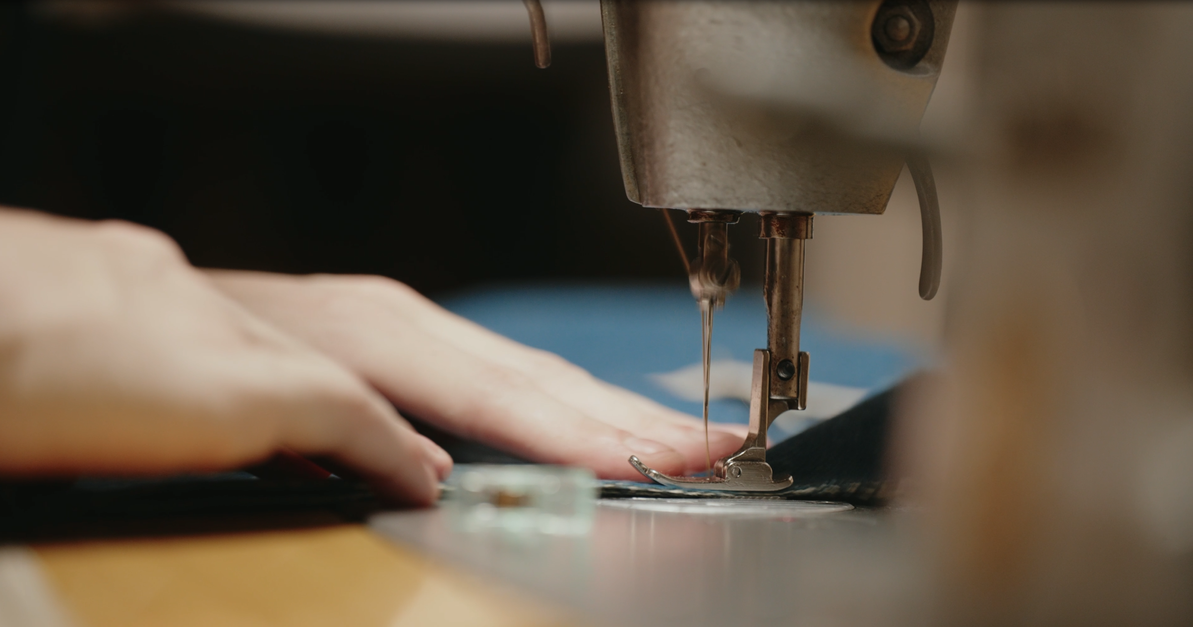Close-up of a person's hands guiding fabric under a sewing machine needle as it stitches the material.