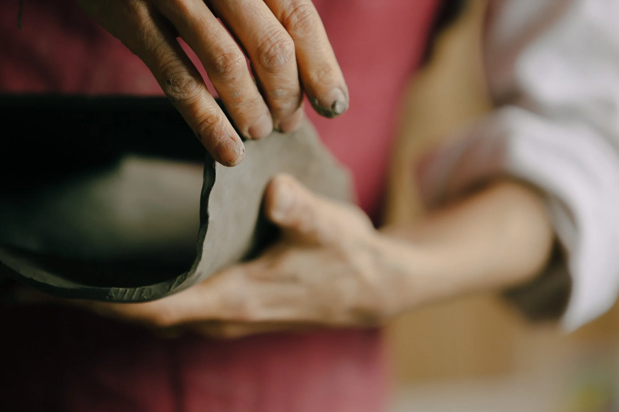 Ottavia Sitia's hands working on a ceramic sculpture - only her hands and a detail of the piece are visible.
