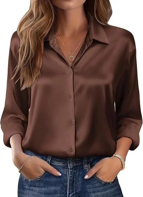 A woman wearing a satin brown button-up shirt with rolled sleeves, paired with blue jeans, and accessorized with a gold necklace and bracelet.