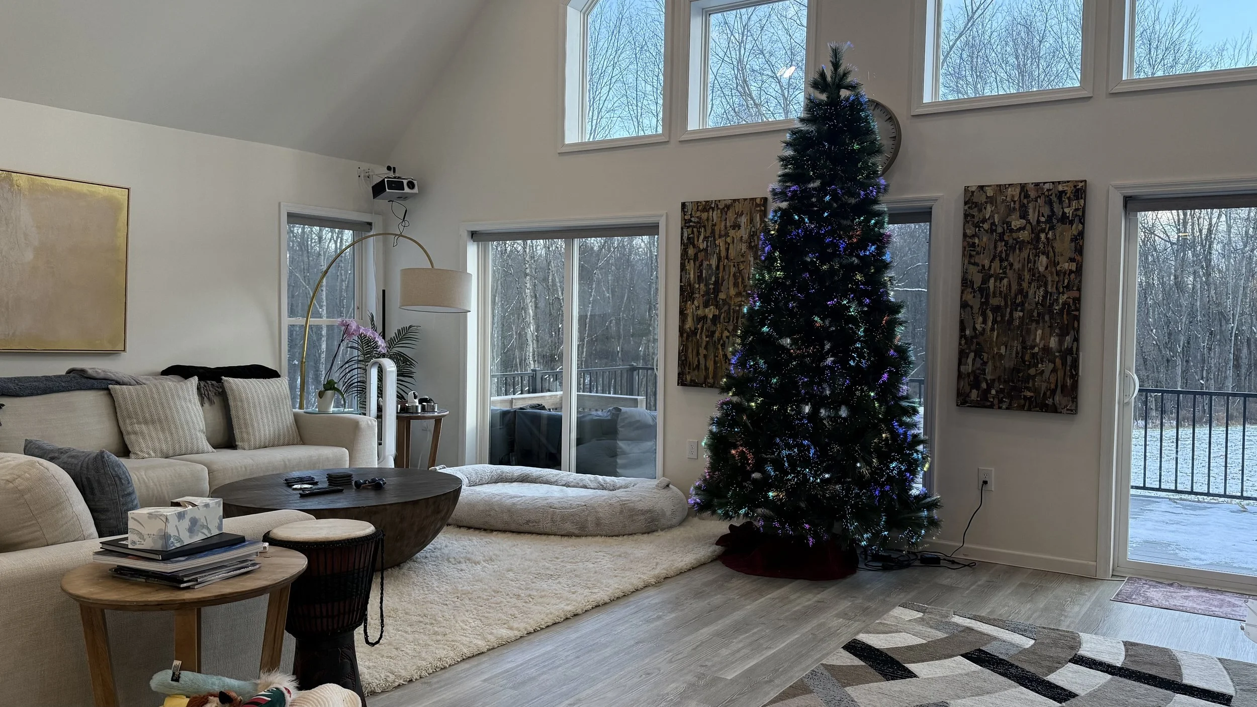 A cozy living room corner with a vintage armchair and sofa, a floor lamp, a small side table, and a bookshelf near a window with natural light.