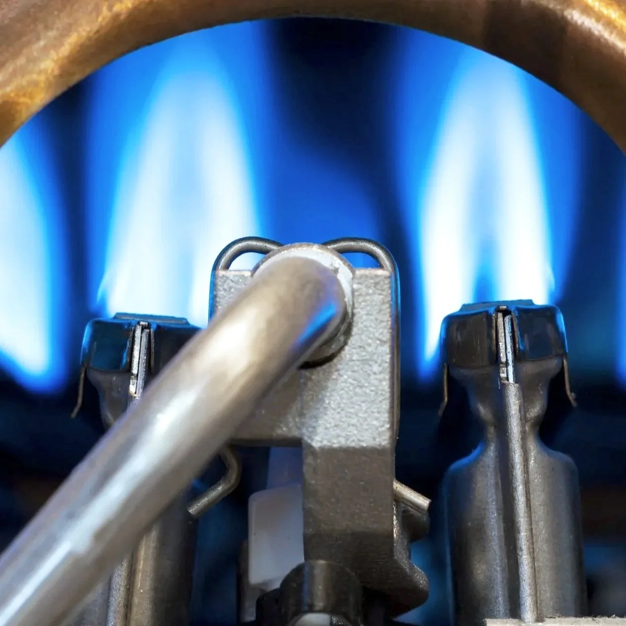 Close-up of a gas stove burner with blue flames.