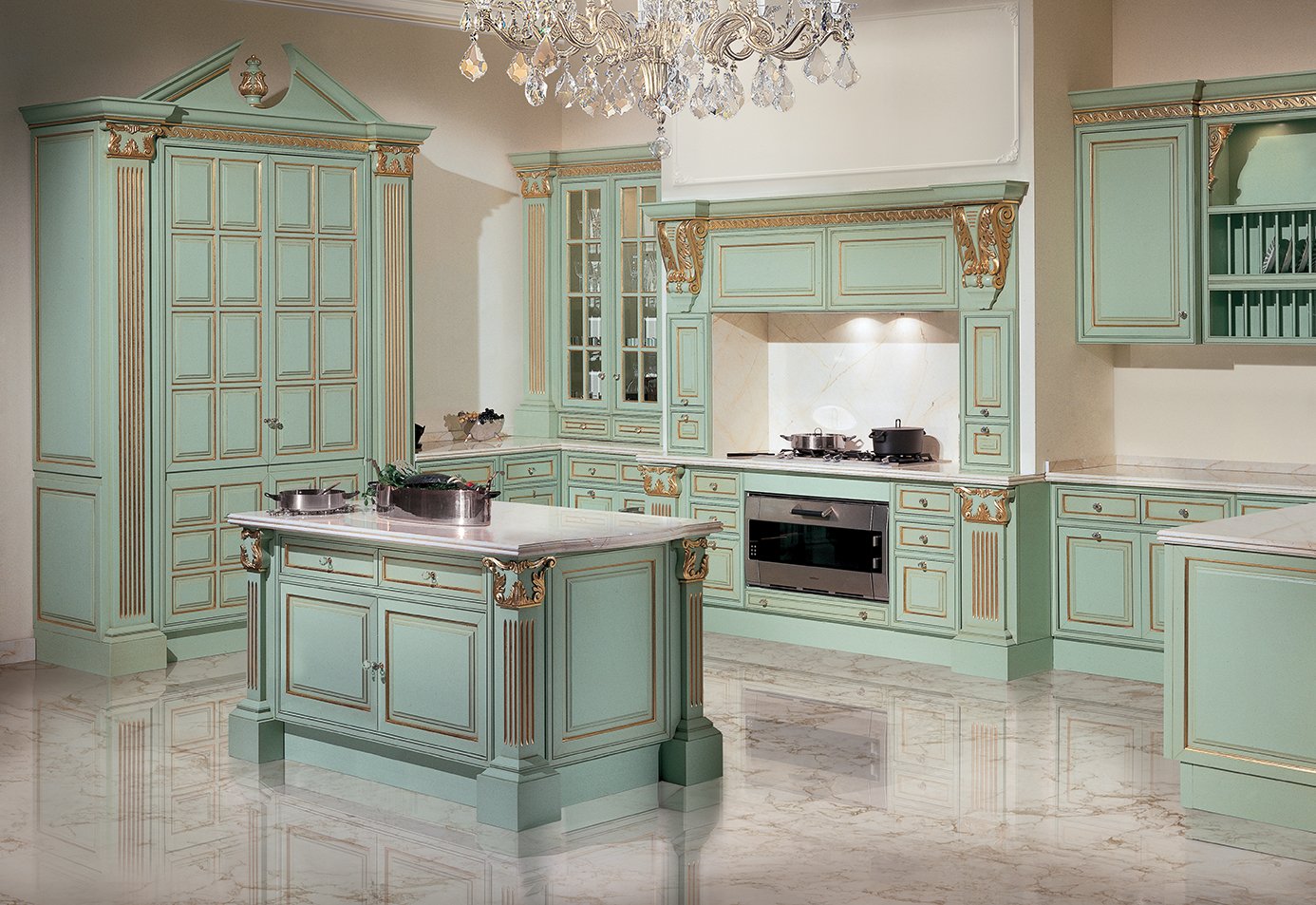 Elegant kitchen with mint green cabinets decorated with gold accents, a marble island, and a chandelier hanging from the ceiling.