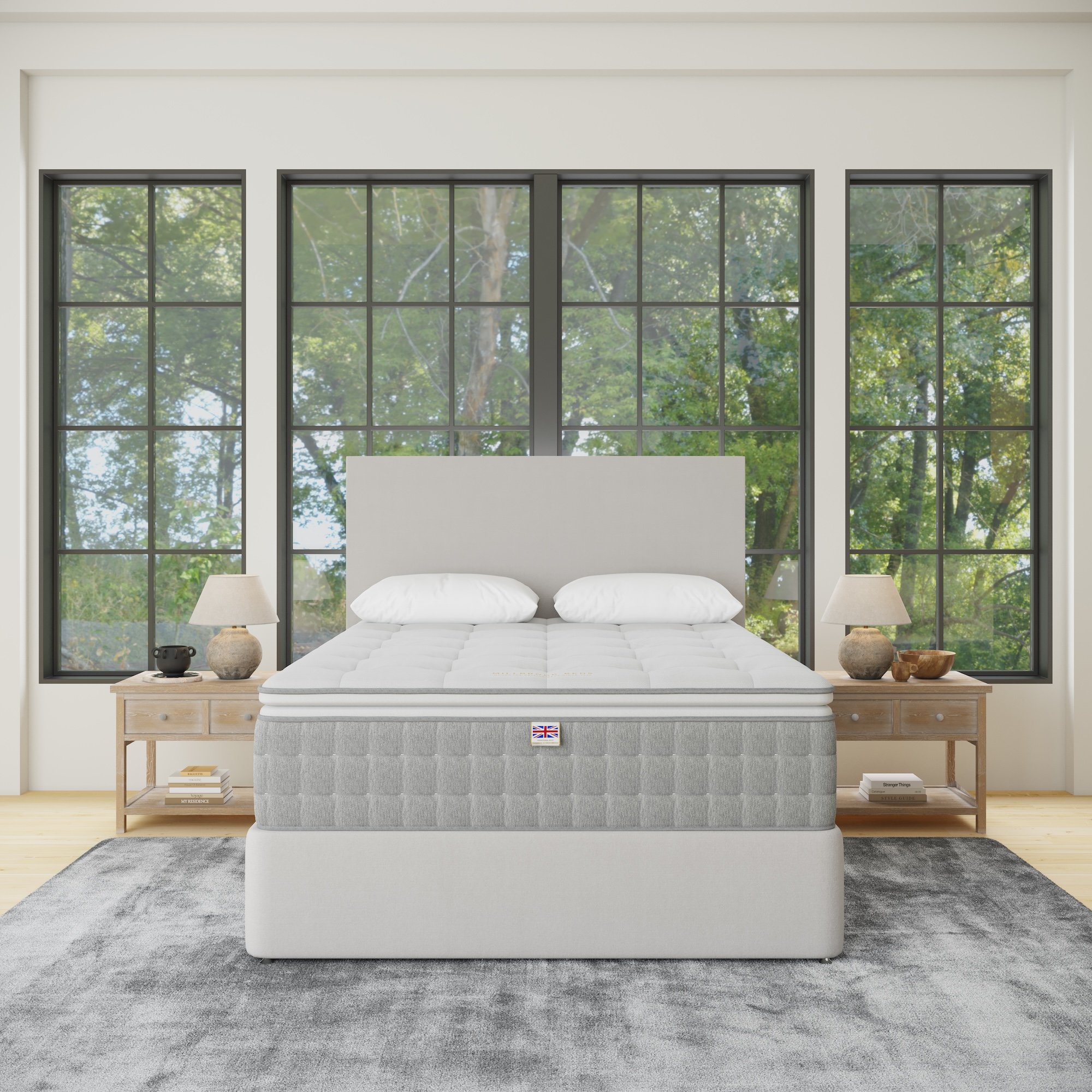 A bedroom with a large bed, two nightstands with lamps, and large windows showing trees outside.