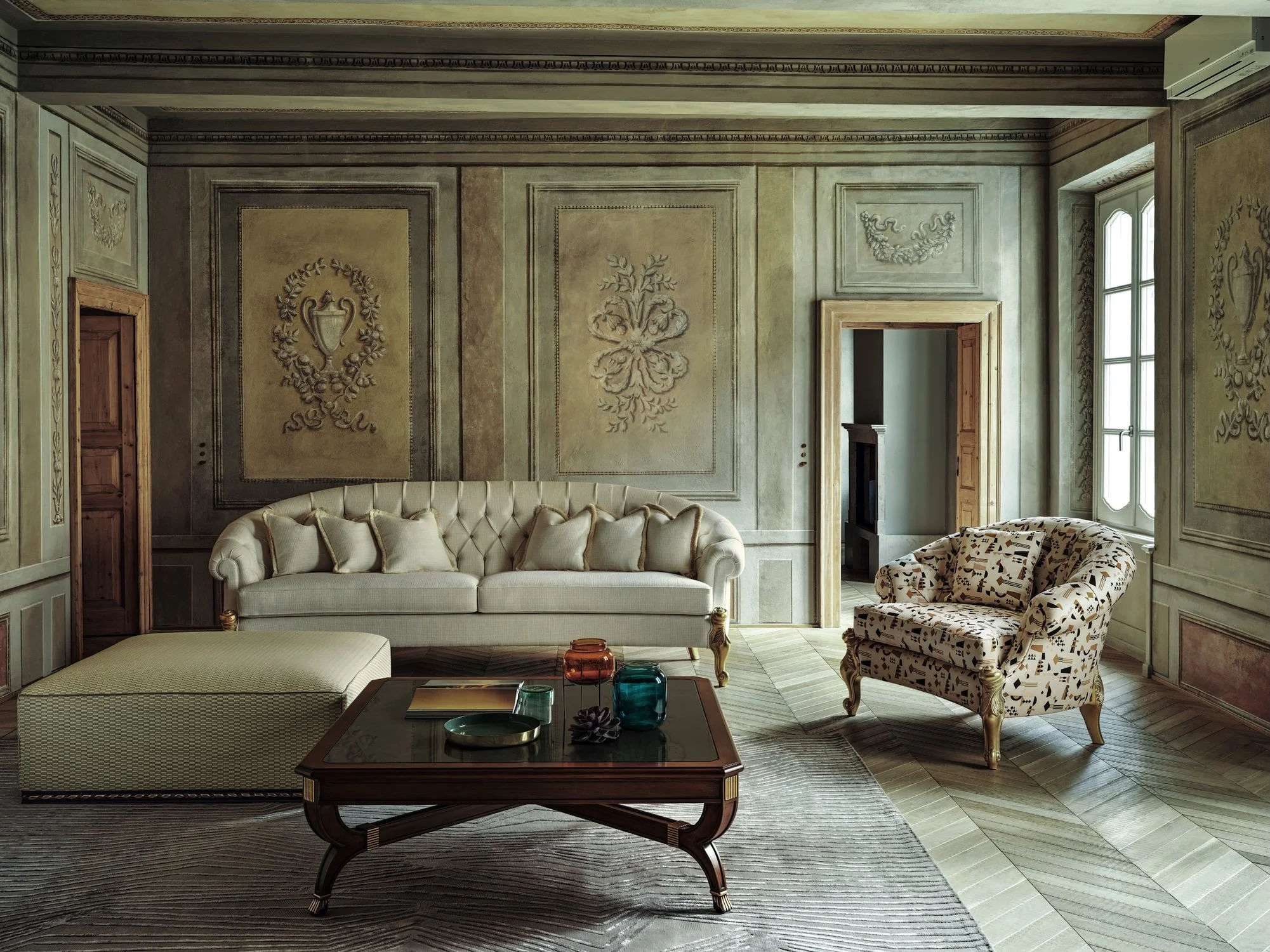 Elegant living room with a tufted beige sofa, patterned armchair, wooden coffee table with colorful glass vases and a tray, ornate wall panels, large window, and light-colored wooden flooring.