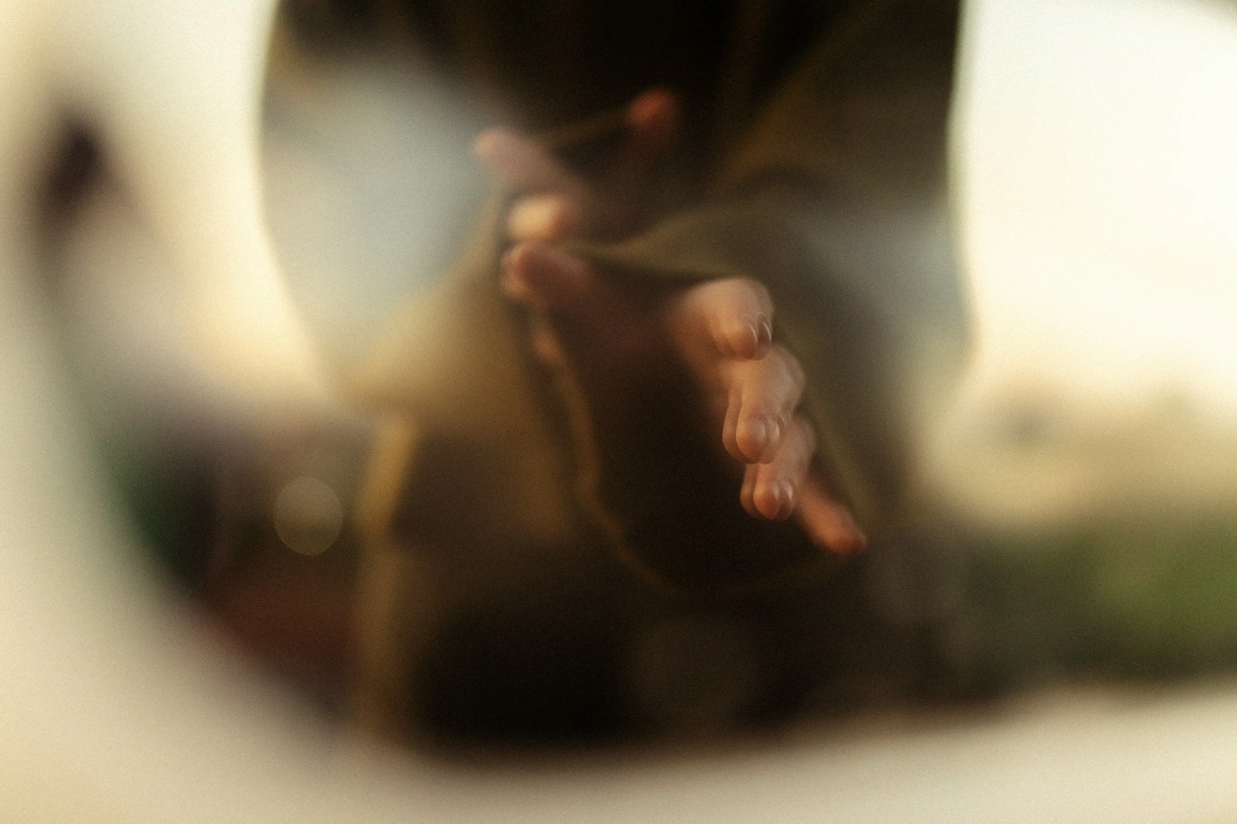 Blurry close-up of a woman's face with closed eyes, dark hair, and light skin, in a dimly lit environment.