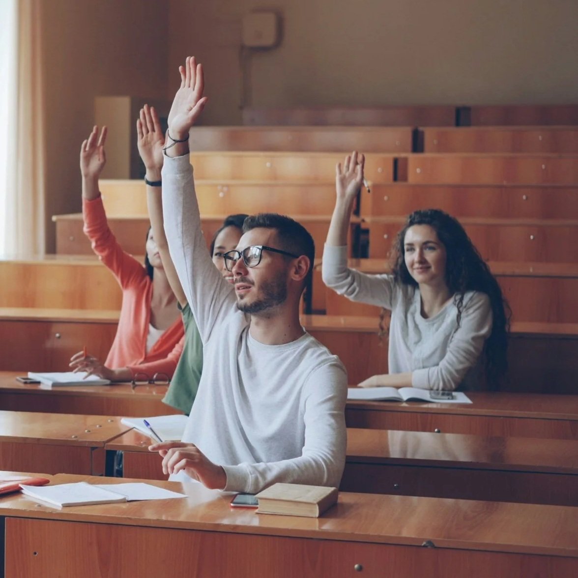 Students in a classroom raising their hands to answer a question.