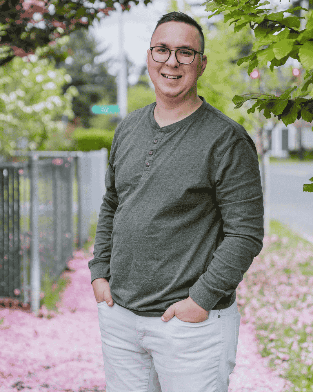 a man stands under a cherry blossom tree and smiles happily at the camera