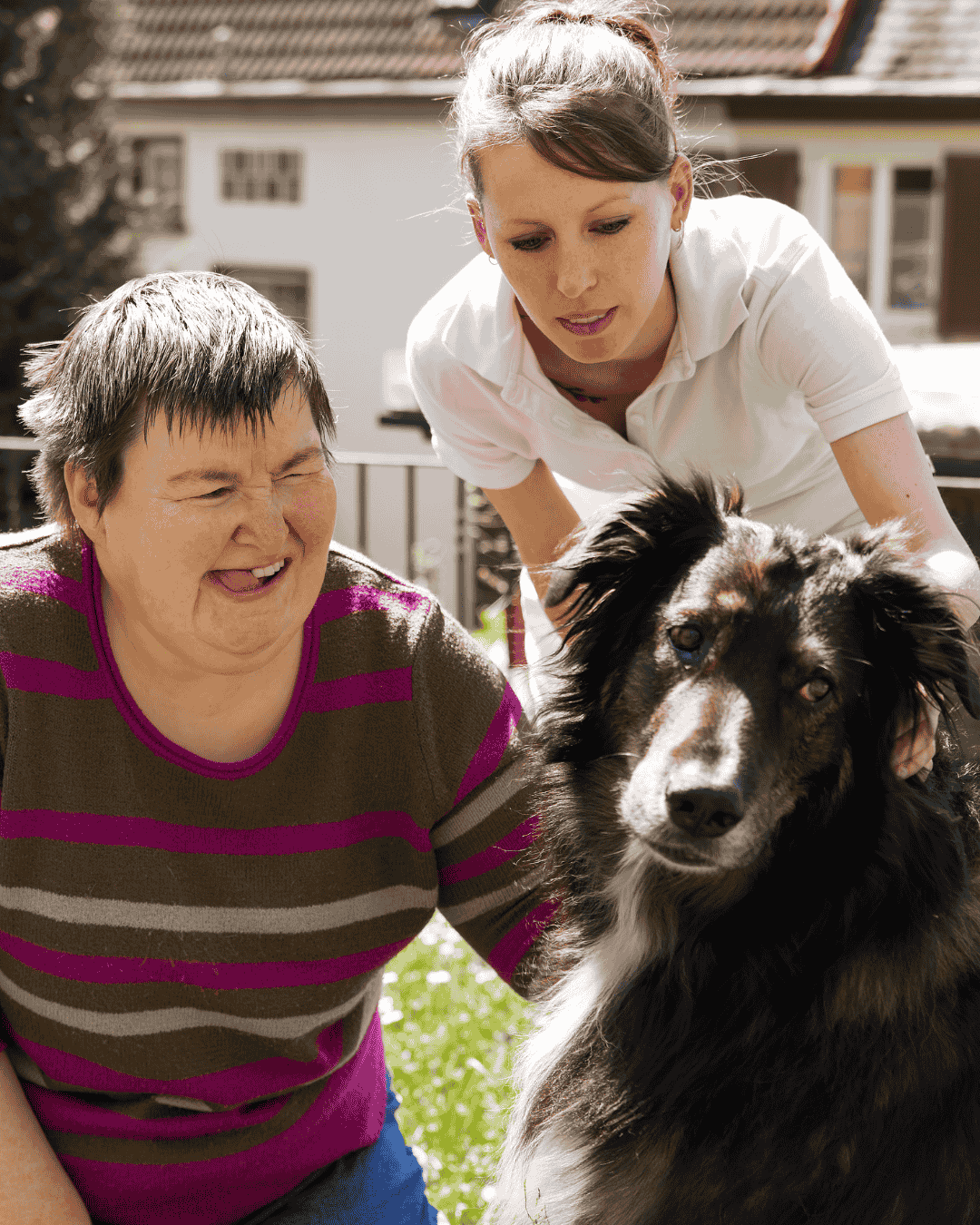 a woman with autism pets a dog while her carer looks on