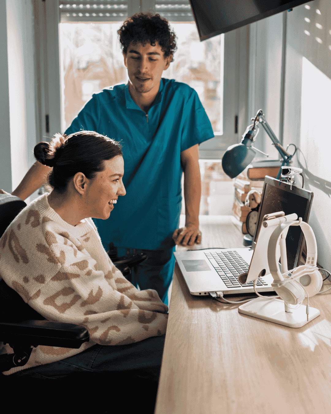 a young man helps a disabled woman to use her laptop
