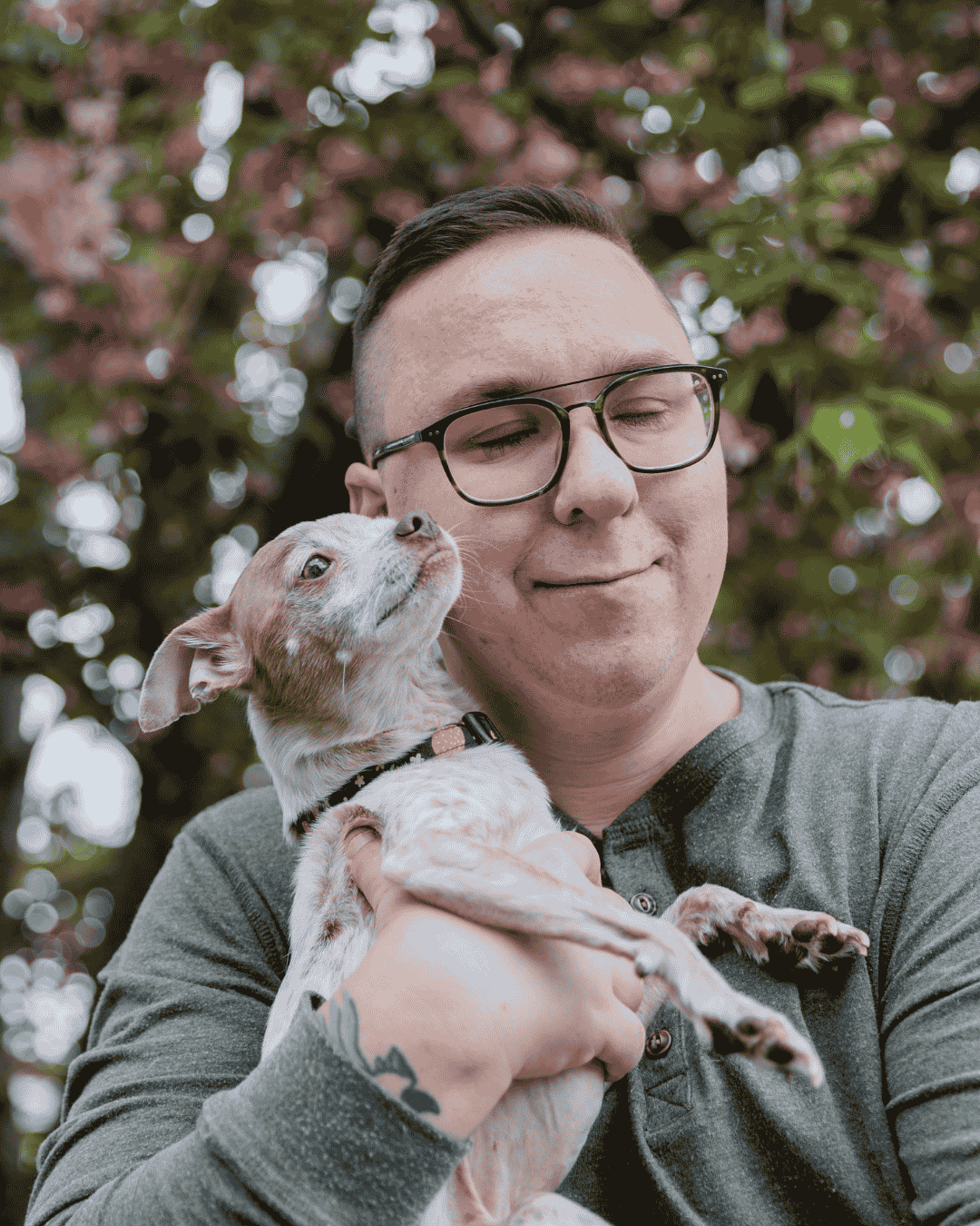 a man hugs a small dog happily