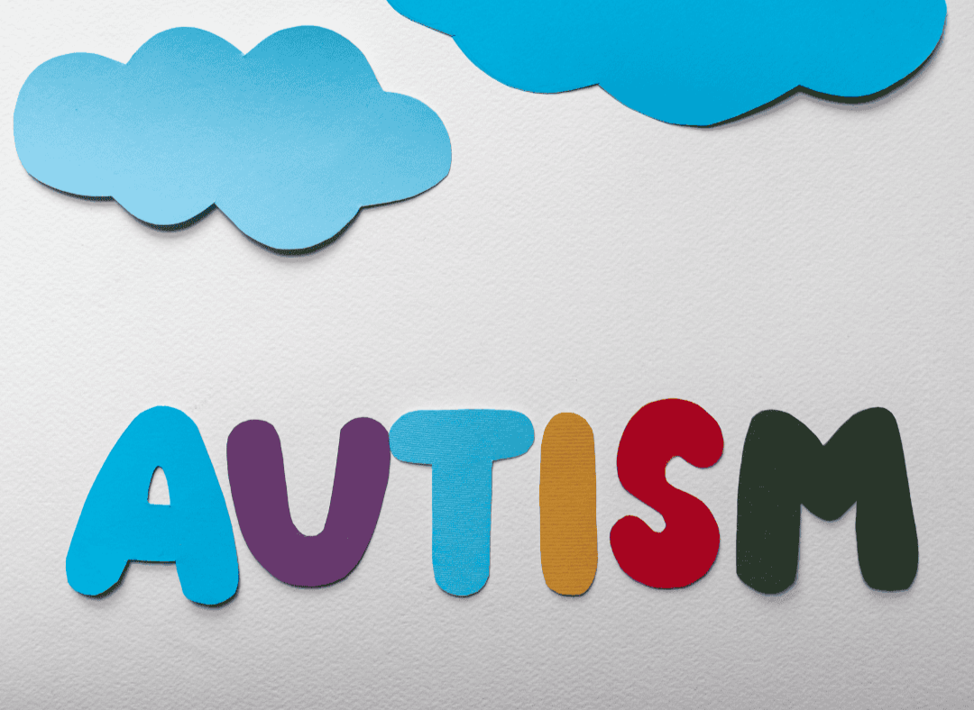 Colorful paper cutouts spelling 'Autism' with blue clouds above on a white background.