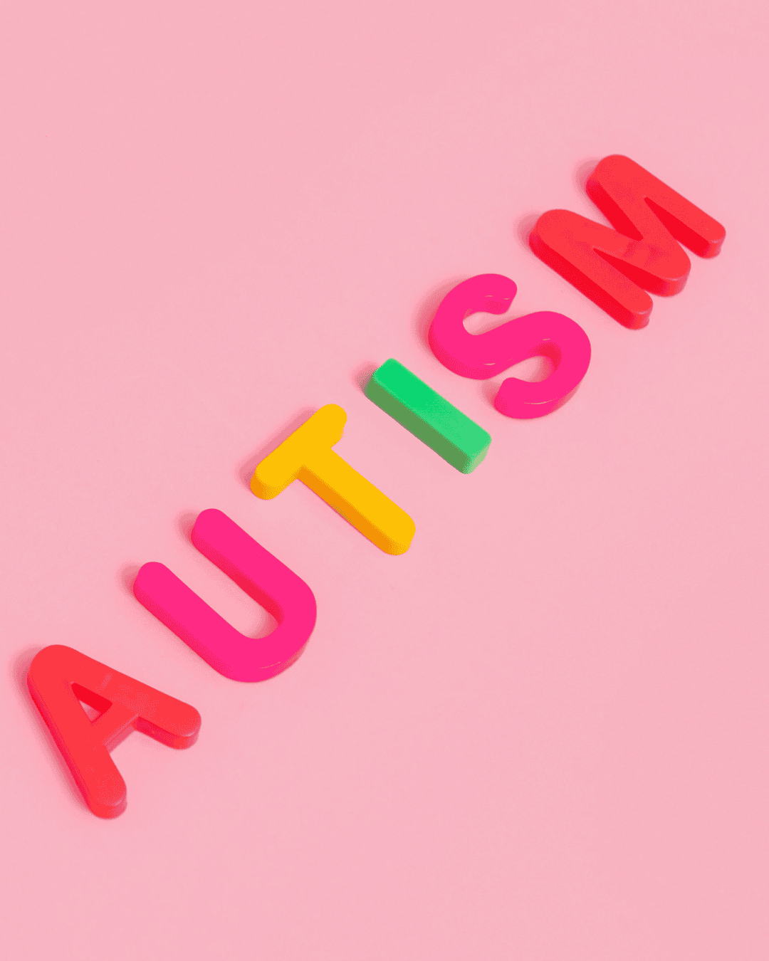 alphabet blocks on pink background spelling autism