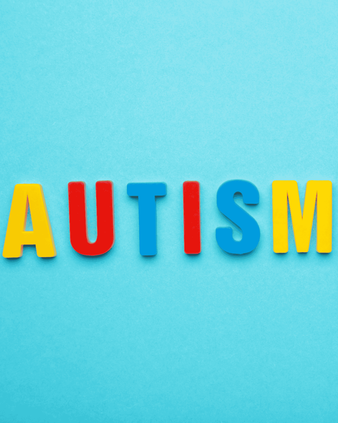 Colorful plastic letters spell out "AUTISM" against a light blue background.