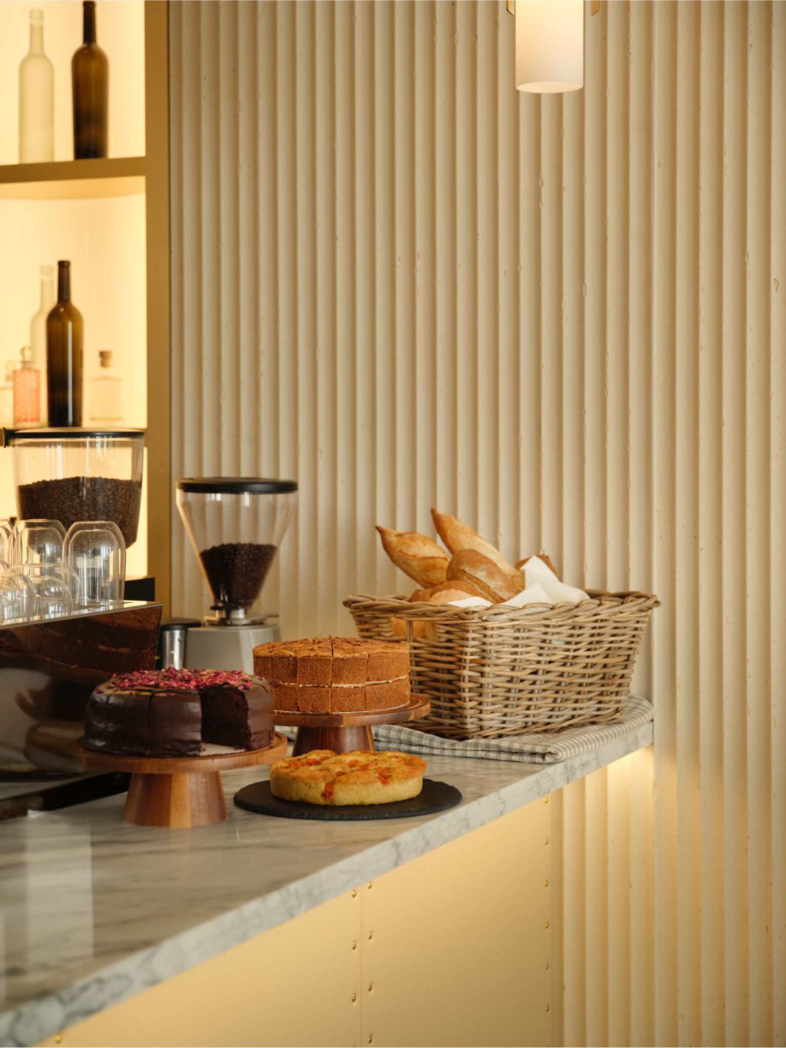 Assorted baked goods including cakes, bread, and focaccia on a marble countertop in a bakery setting.