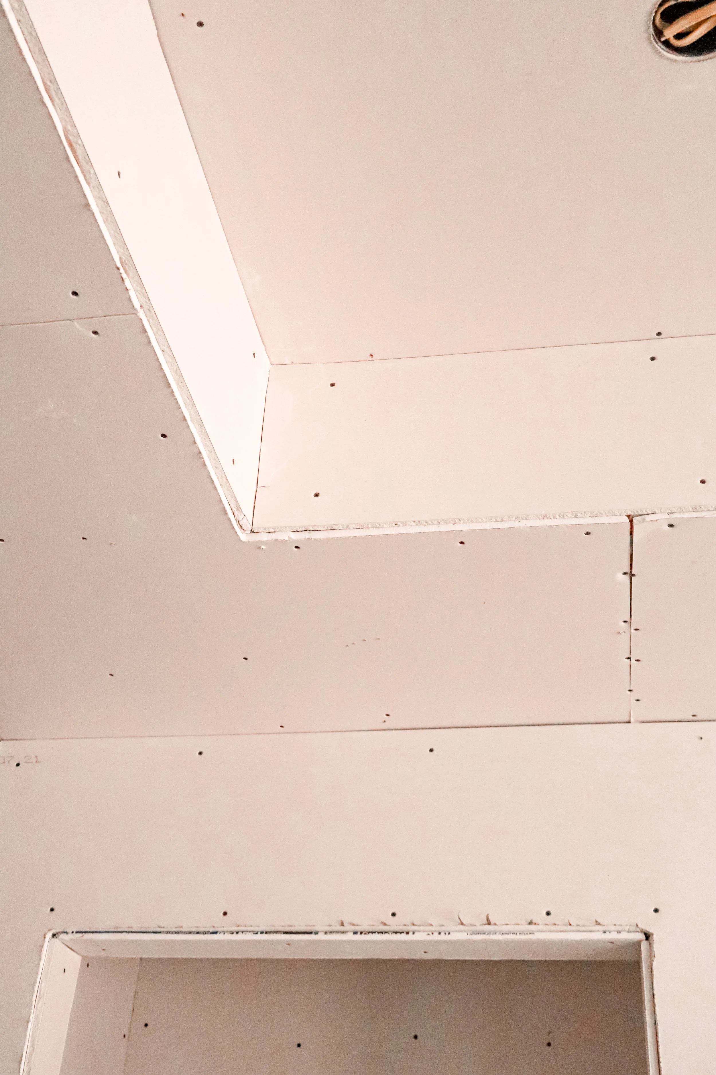 Ceiling with drywall panels and screw holes visible.