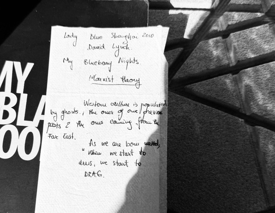 Handwritten cultural notes on a napkin over a black notebook, referencing film, identity, and Western culture.