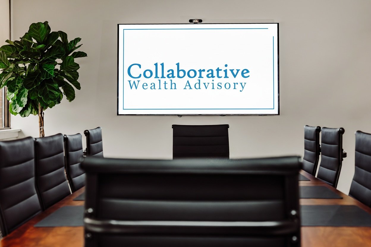 Conference room with a large table surrounded by black chairs, a green plant in the corner, and a screen displaying 'Collaborative Wealth Advisory'.