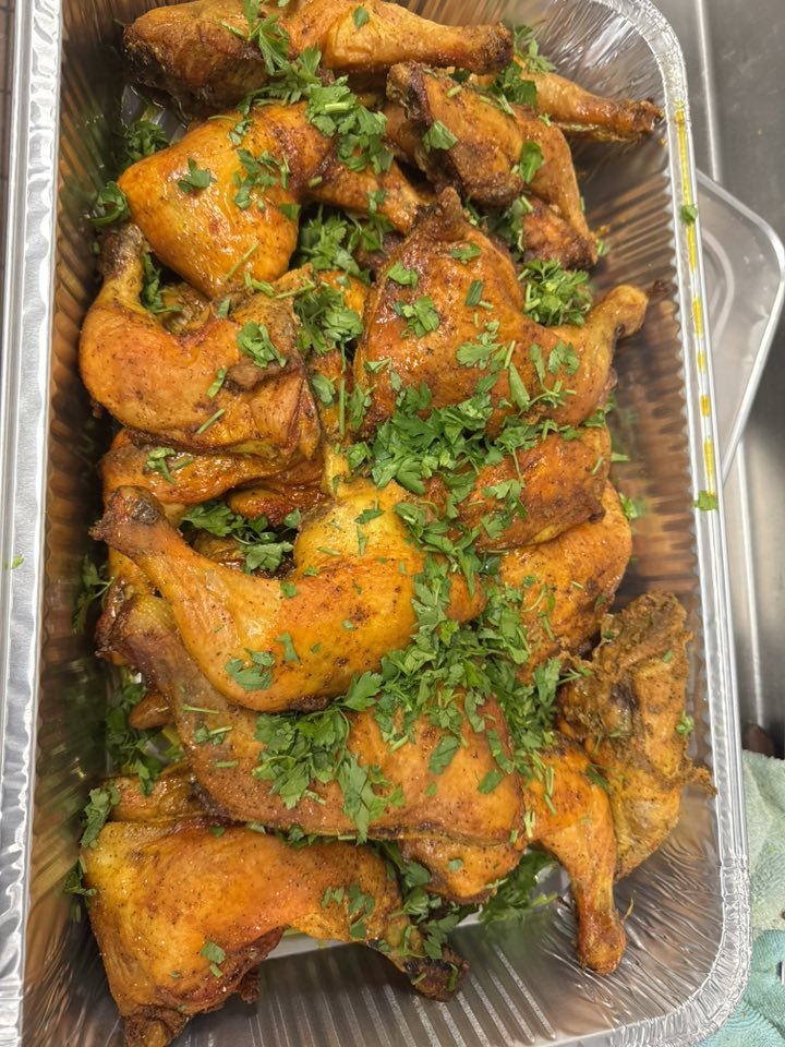 A container of cooked chicken drumsticks garnished with chopped cilantro.