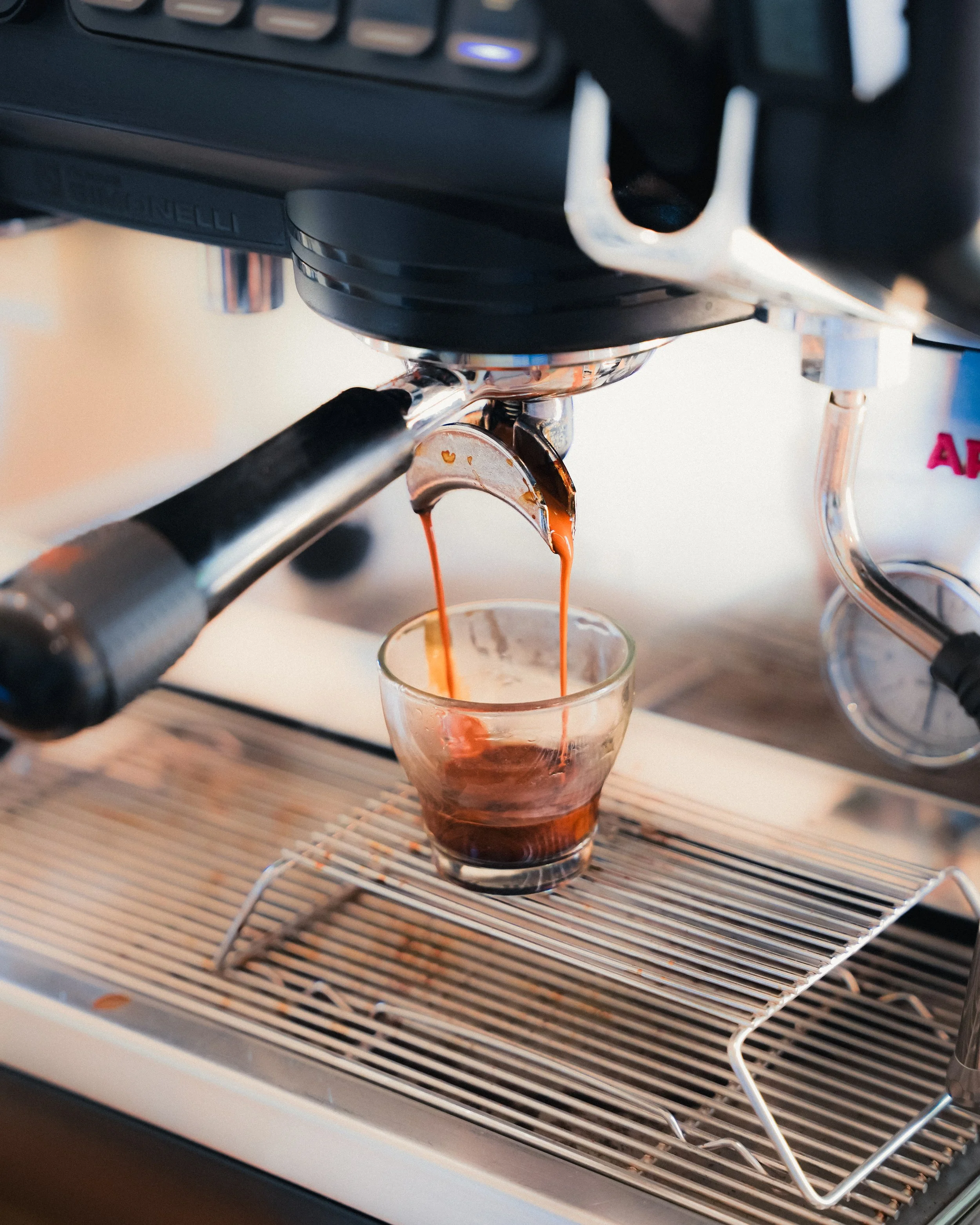 Close-up of an espresso machine pouring dark coffee into a glass cup.