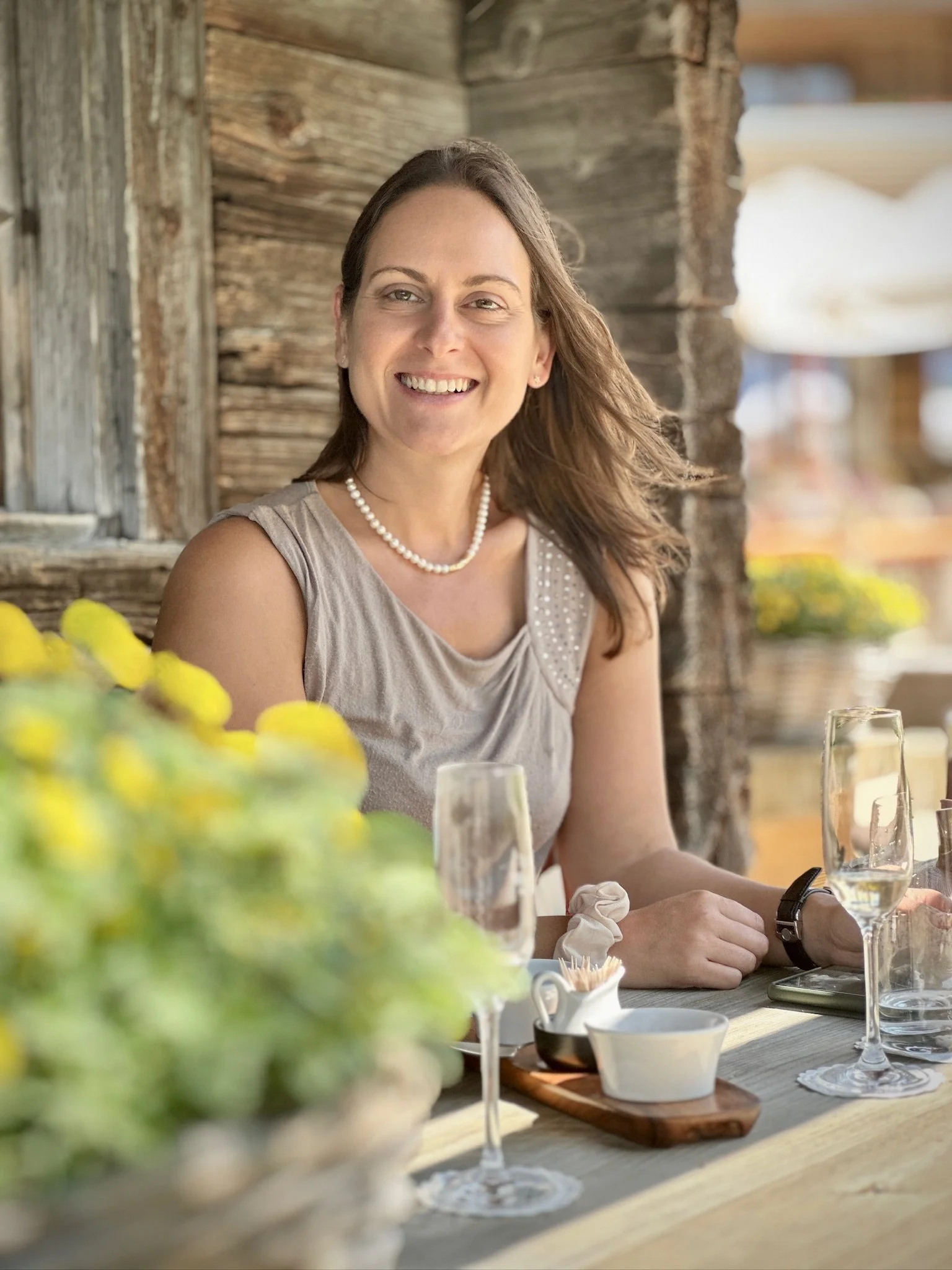 Joëlle Gautier sitzend an einem Holztisch im Hotel Hornberg in Saanen auf im Garten bei sonnigem Wetter.