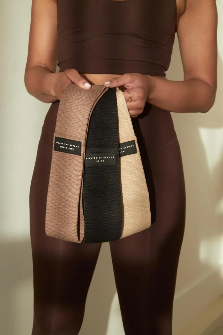 Žena oblečená v pilates oblečení držící prémiové elastické odporové gumy na cvičení reformer pilates