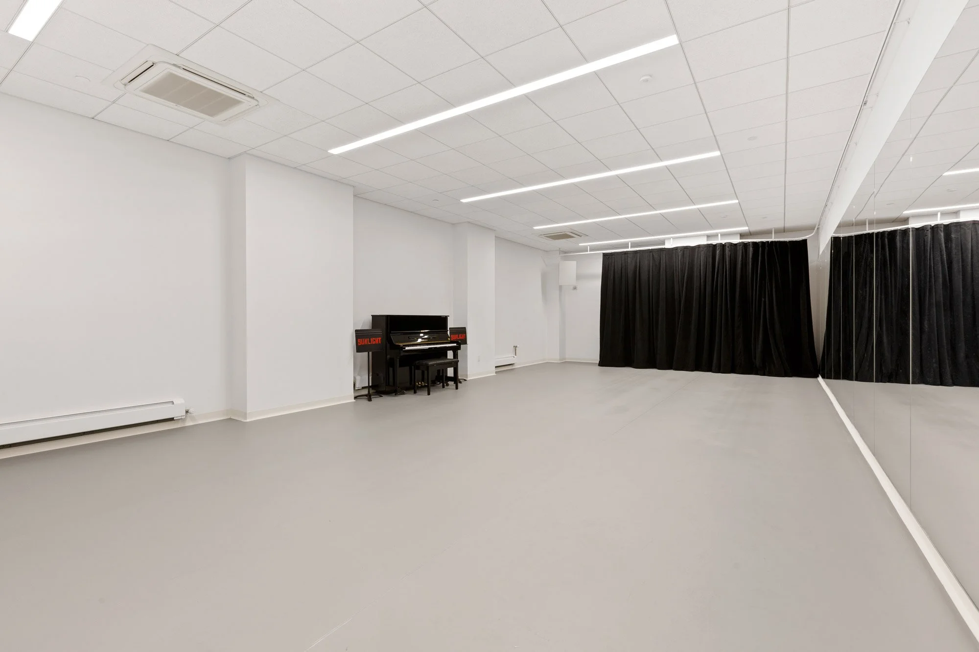 large rehearsal room with marley floors, mirrors and piano