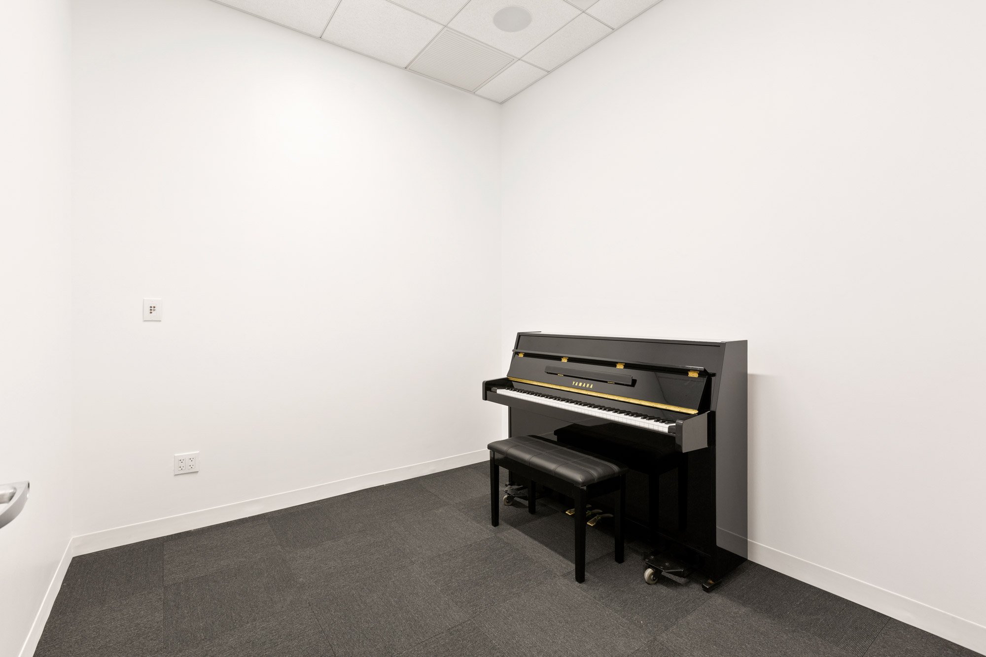 small rehearsal studio with carpet and piano