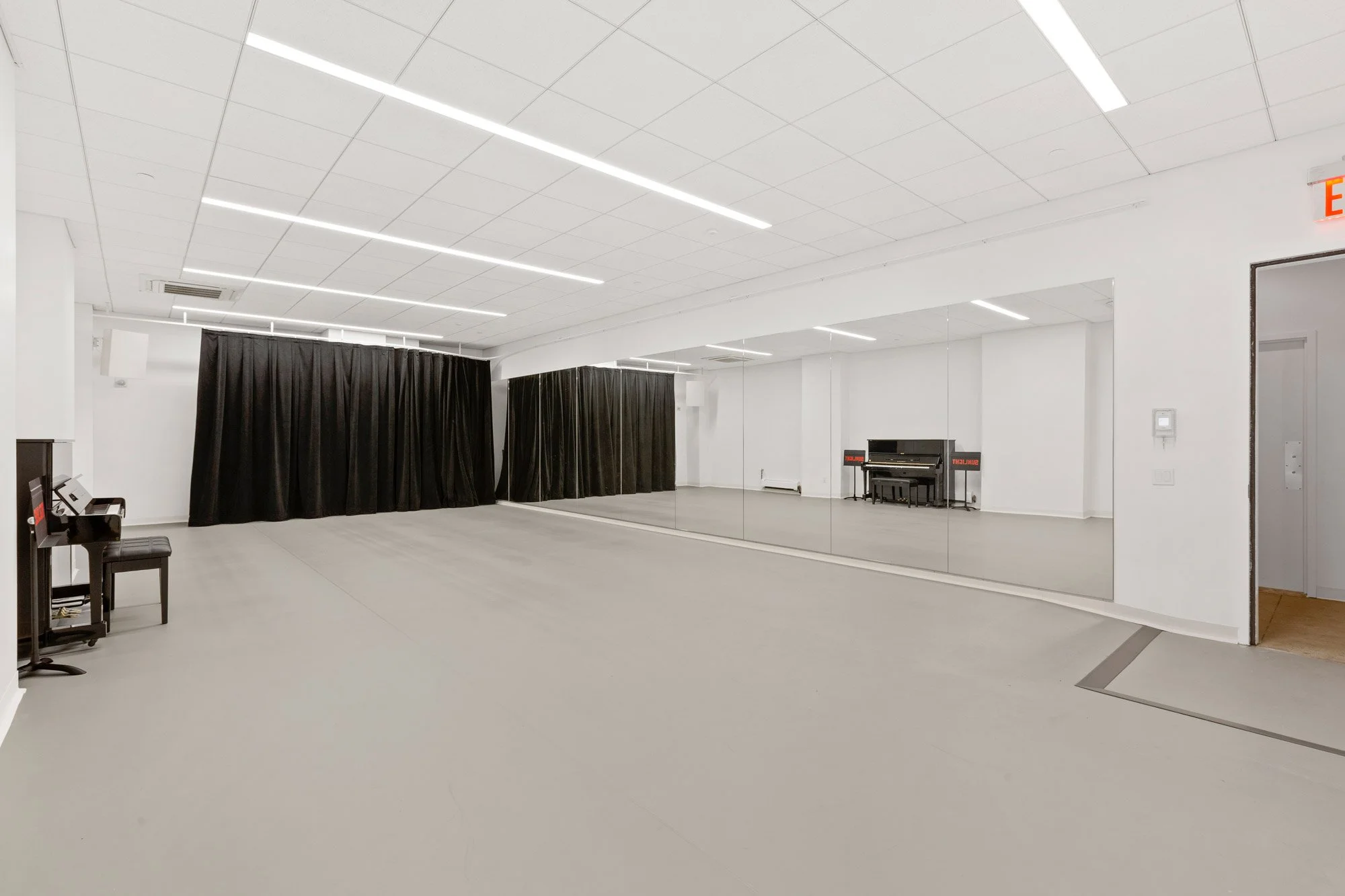 large rehearsal room with marley floors, mirrors and piano