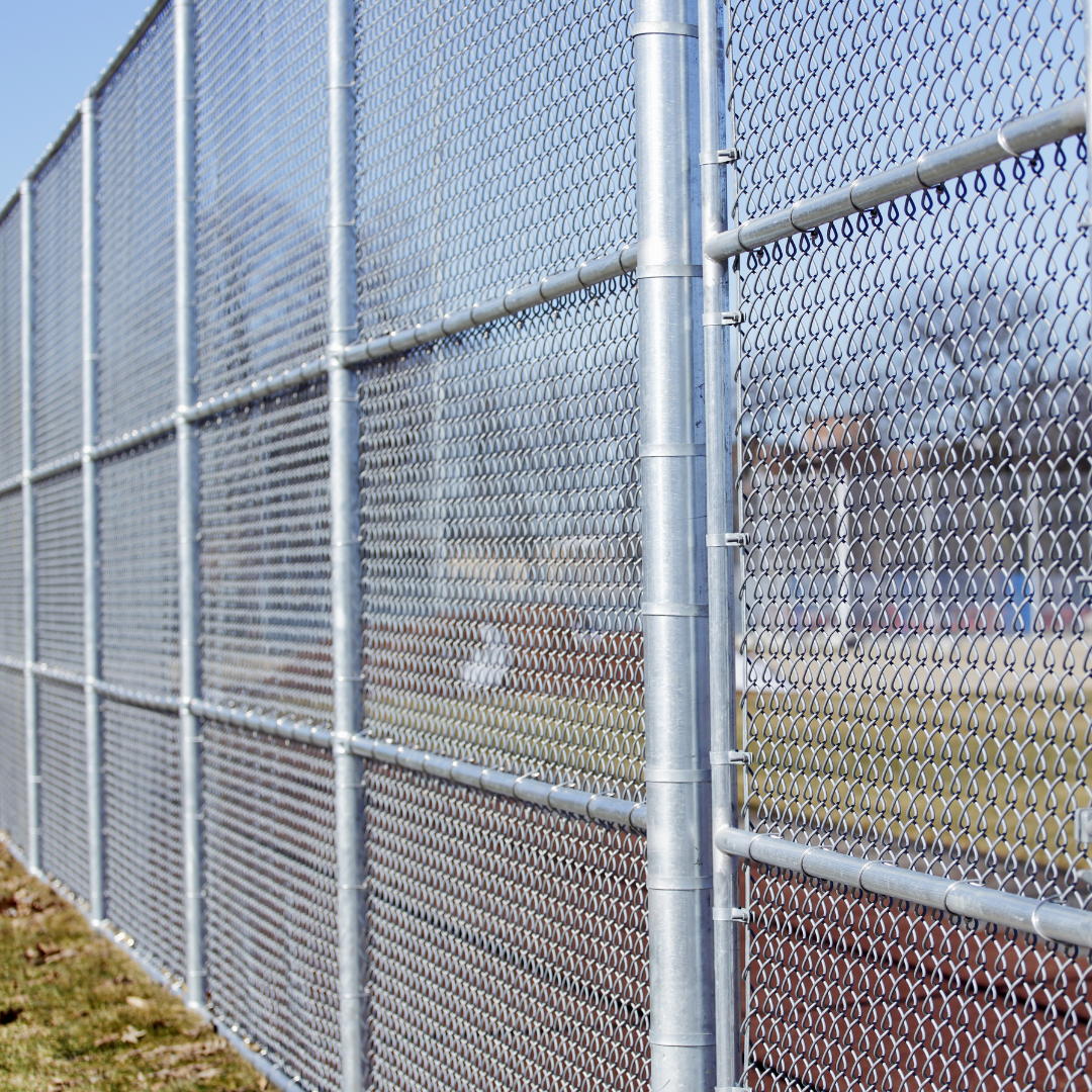 Close-up of a chain-link fence with metal posts and supports, outdoors under a clear sky.