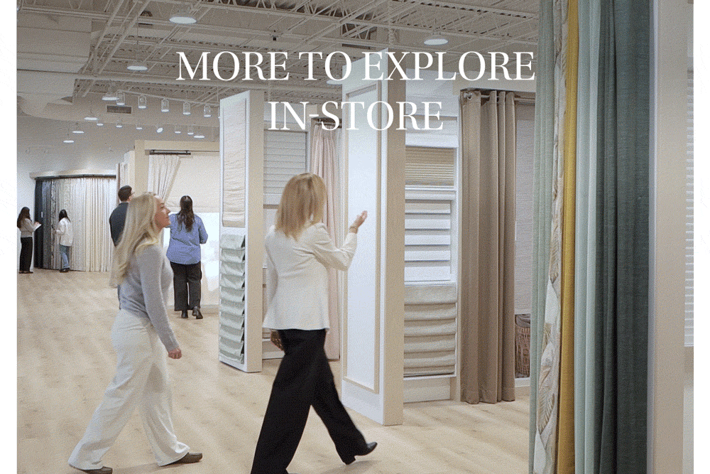 Interior of a home decor store with fabric samples and curtains on display, and a few shoppers browsing.