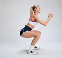 A woman in workout clothes performing a squat exercise.