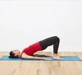 Woman practicing bridge pose on yoga mat in a bright room
