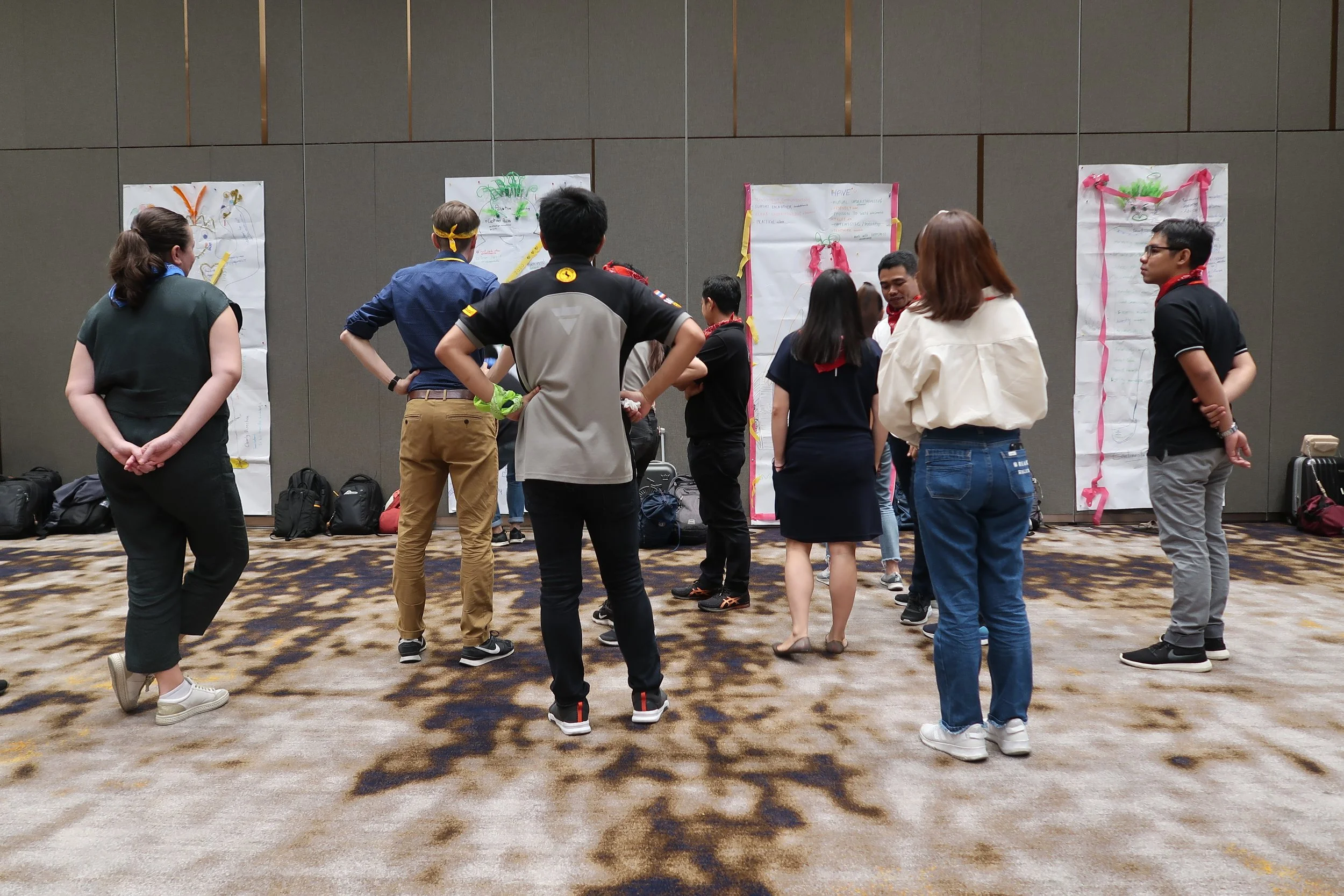 A group of people gathered in front of decorated posters on a wall at an indoor event.