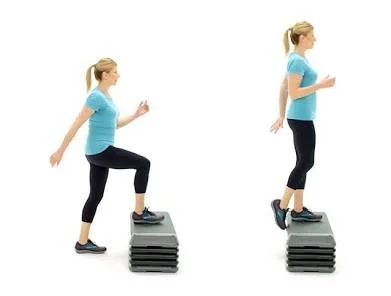 A woman in workout clothes performing step-up exercise on a stack of aerobic steps.