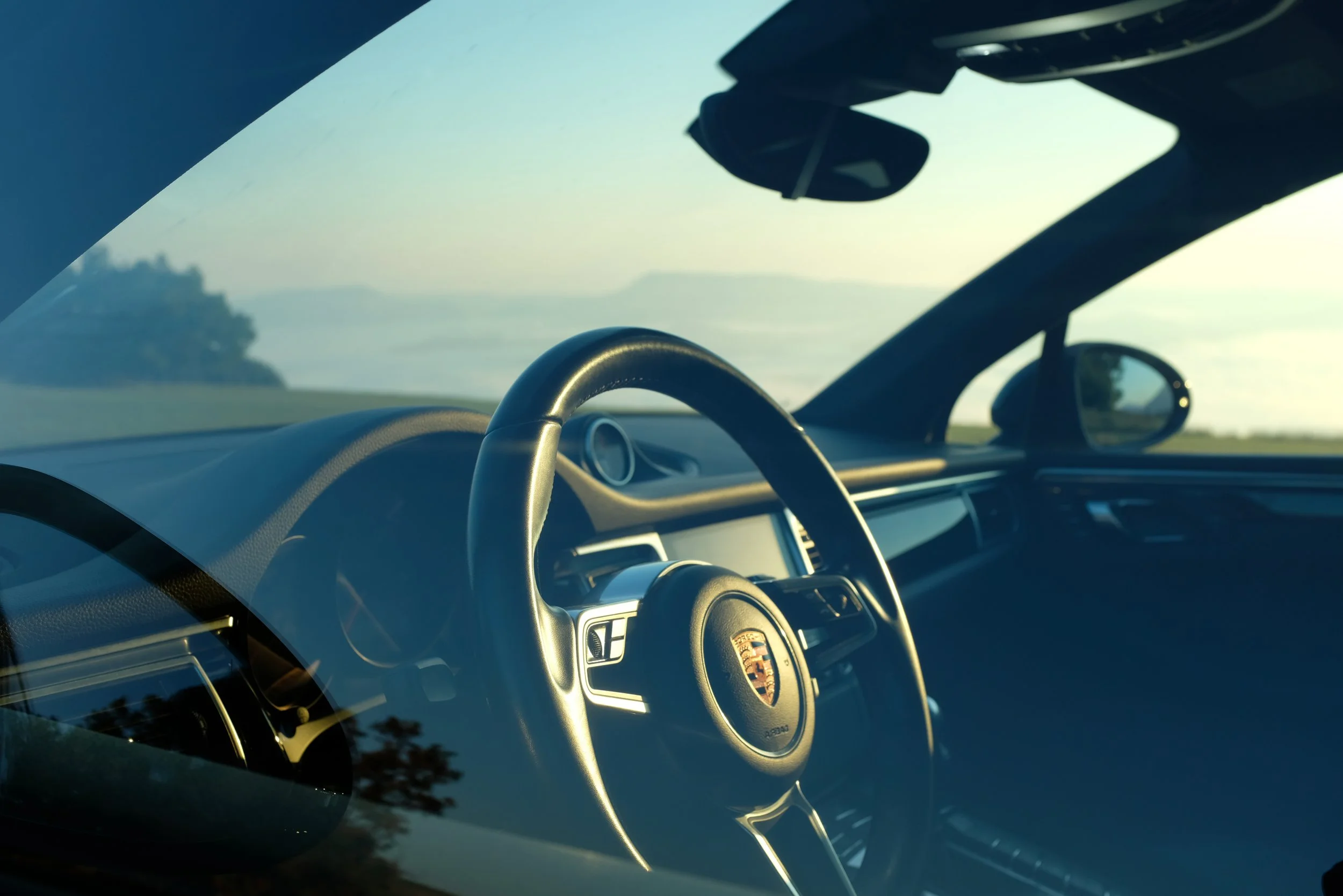 Interno di un'auto Porsche vista attraverso il parabrezza con un paesaggio naturale all'esterno