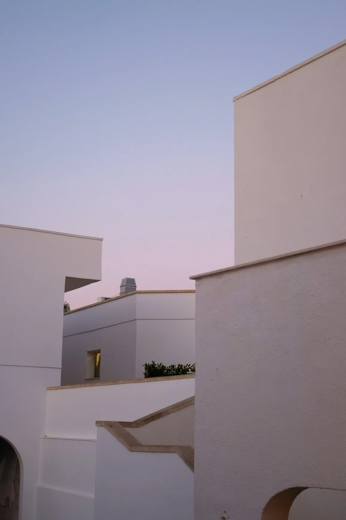 Edifici bianchi con forme geometriche e un cielo al tramonto o all'alba.