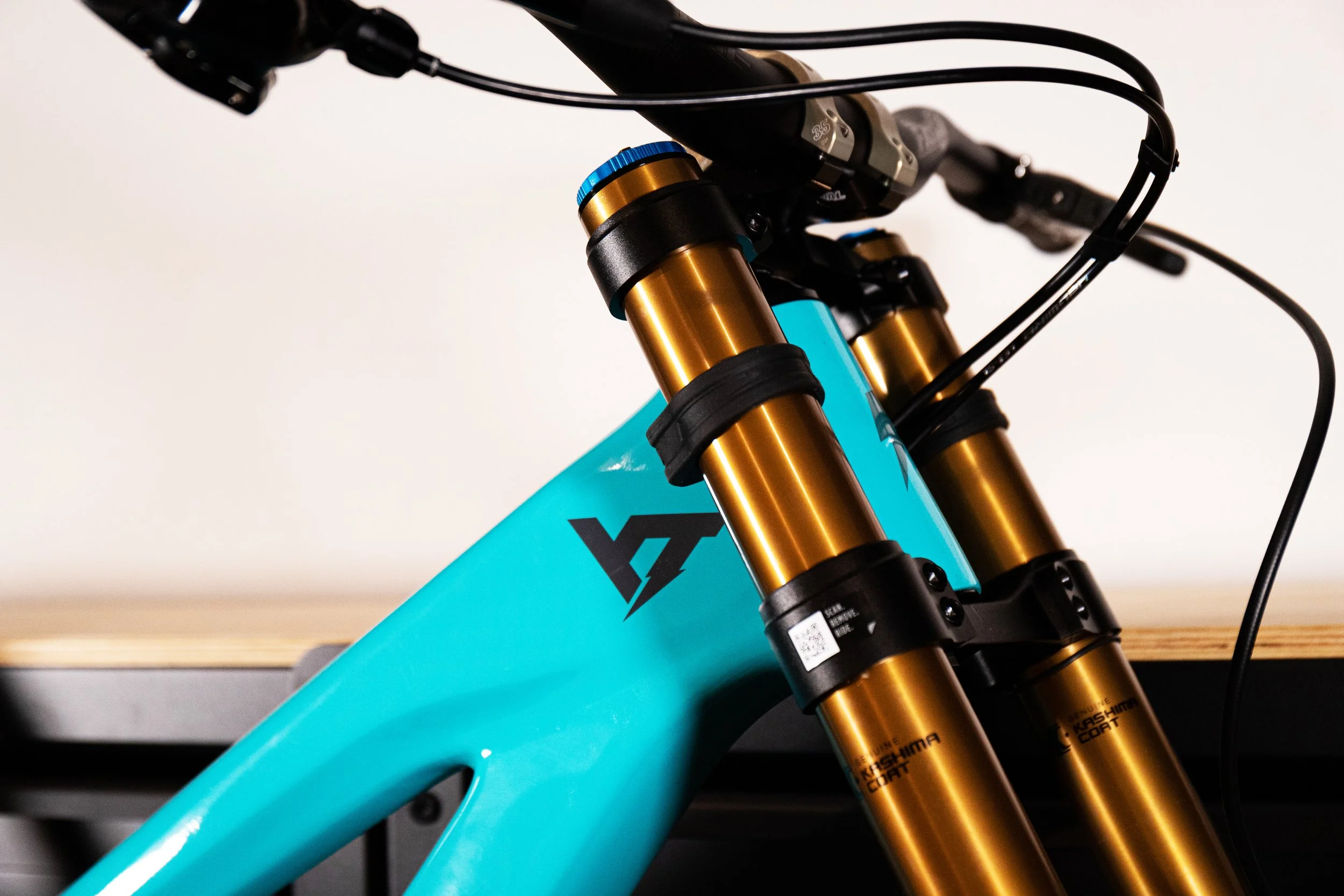 Dettaglio di una motocicletta da montagna con sospensioni dorate e telaio blu, evidenziando la forcella anteriore e il manubrio.